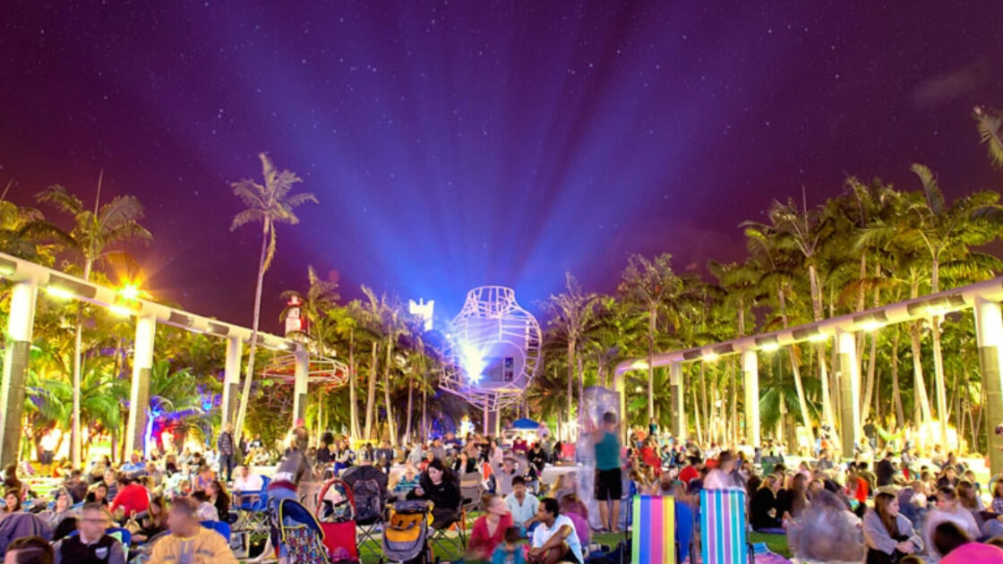 A crowd on the lawn at SoundScape Park for an outdoor movie night on the New World Center wall